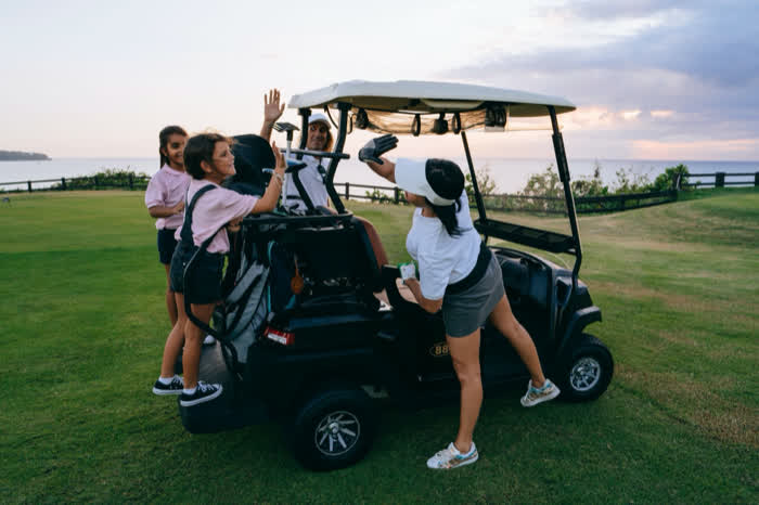 A group climbing aboard a golf cart